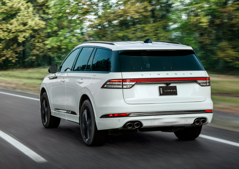 A white 2025 Lincoln Aviator® SUV is being driven away down a road lined with colorful trees. | Lincoln Demo 2 in Wooster OH